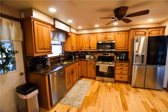 kitchen featuring ceiling fan, sink, stainless steel appliances, and light hardwood / wood-style flooring