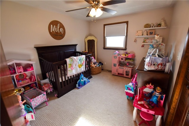 carpeted bedroom featuring a nursery area and ceiling fan