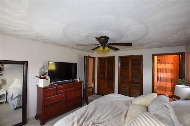 carpeted bedroom with multiple closets and ceiling fan