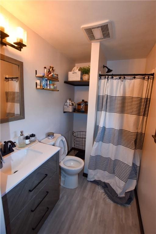 bathroom with hardwood / wood-style floors, vanity, a shower with shower curtain, and toilet