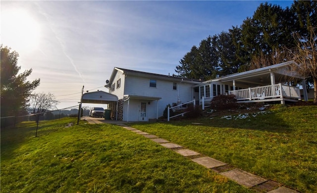 back of property with a carport and a lawn