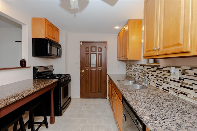 kitchen featuring decorative backsplash, light stone counters, sink, and appliances with stainless steel finishes