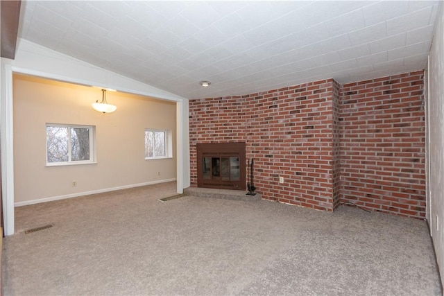 unfurnished living room with carpet flooring, a fireplace, brick wall, and lofted ceiling