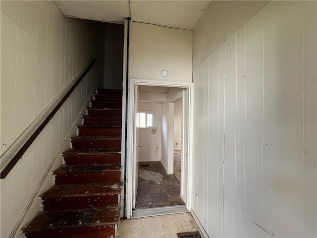 staircase featuring wooden walls