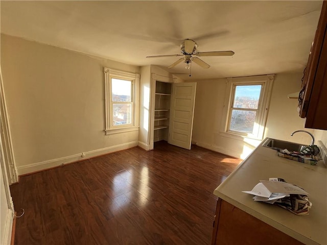 unfurnished bedroom with multiple windows, ceiling fan, sink, and dark hardwood / wood-style floors