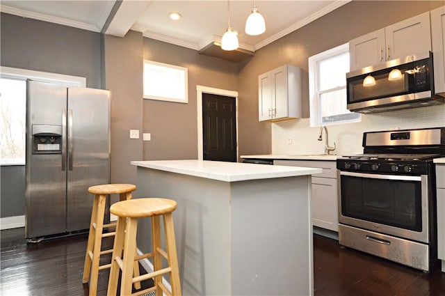 kitchen featuring a kitchen bar, white cabinets, decorative light fixtures, and appliances with stainless steel finishes