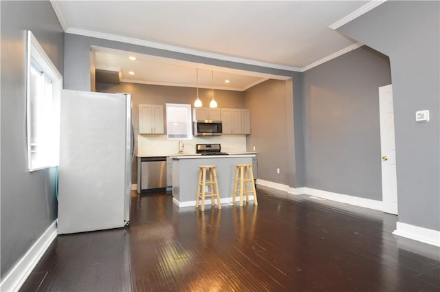 kitchen featuring a center island, crown molding, decorative light fixtures, a kitchen bar, and appliances with stainless steel finishes