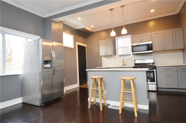 kitchen with backsplash, gray cabinetry, stainless steel appliances, decorative light fixtures, and dark hardwood / wood-style floors