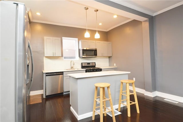 kitchen featuring a center island, pendant lighting, a kitchen bar, white cabinets, and appliances with stainless steel finishes