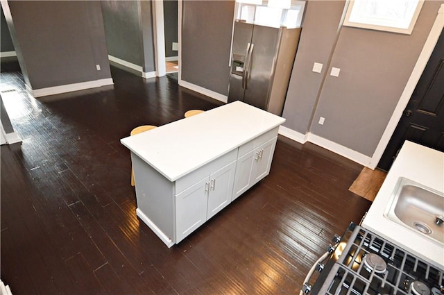 kitchen with white cabinets, sink, stainless steel refrigerator with ice dispenser, dark hardwood / wood-style floors, and a kitchen island