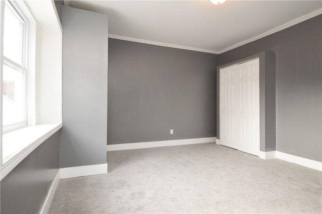 unfurnished bedroom featuring light colored carpet, a closet, and crown molding