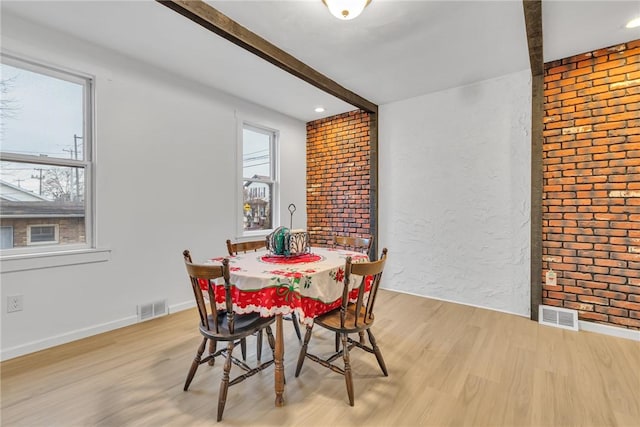 dining space featuring light wood-type flooring and brick wall