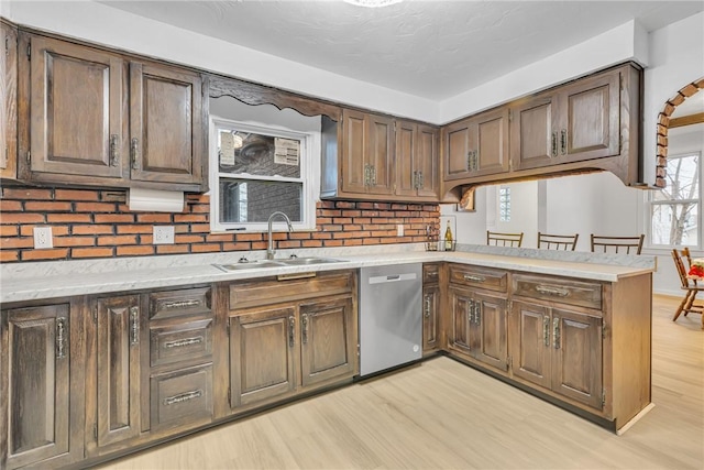 kitchen with kitchen peninsula, dishwasher, light hardwood / wood-style flooring, and sink