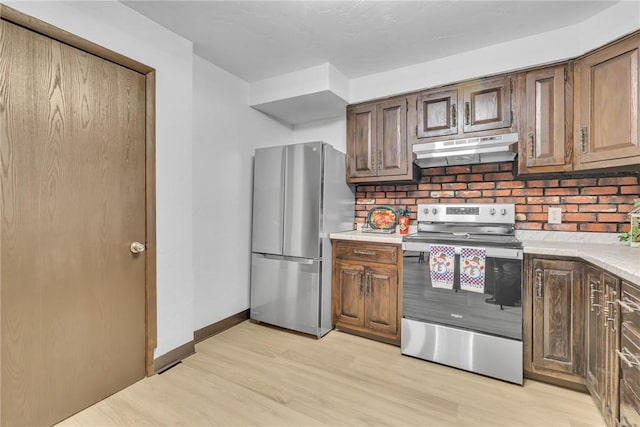 kitchen with decorative backsplash, appliances with stainless steel finishes, and light hardwood / wood-style floors