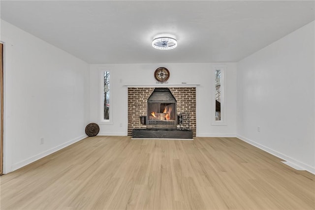 unfurnished living room with a brick fireplace and light wood-type flooring