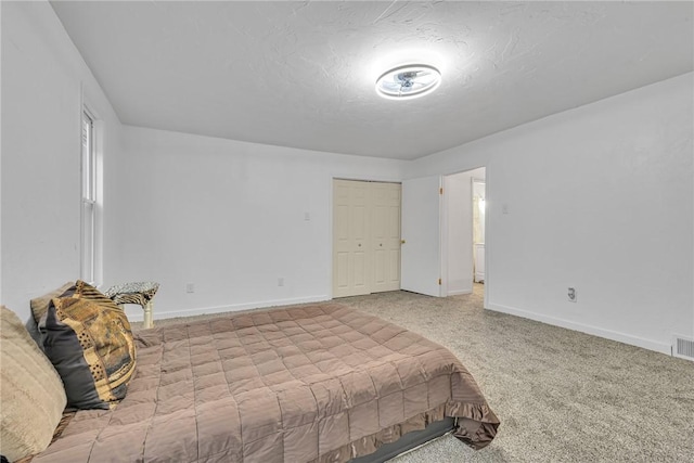 carpeted bedroom featuring a textured ceiling and a closet