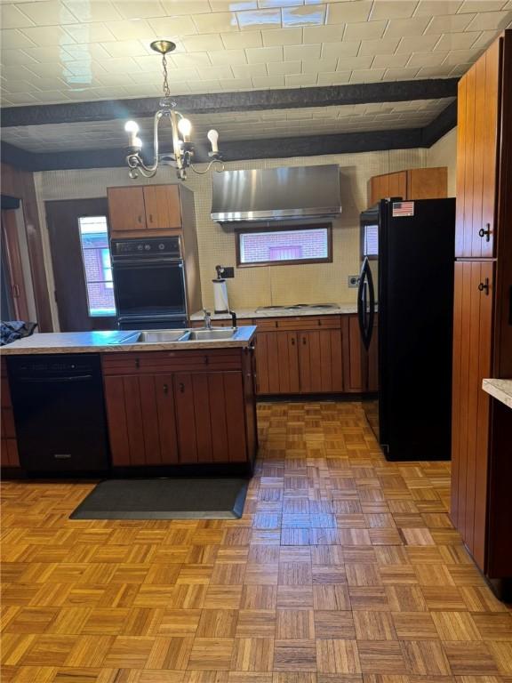 kitchen featuring range hood, a chandelier, pendant lighting, brick ceiling, and black appliances