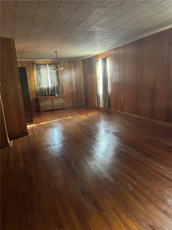 spare room with radiator, wood walls, and dark hardwood / wood-style flooring