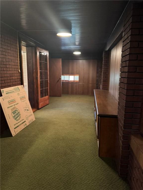 basement with wooden walls, carpet floors, and brick wall