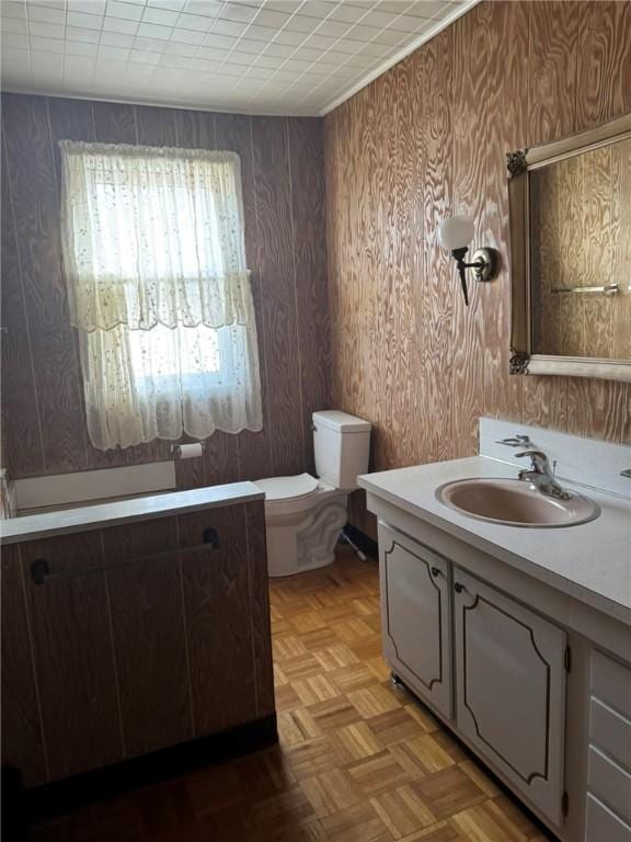 bathroom featuring vanity, toilet, and parquet flooring