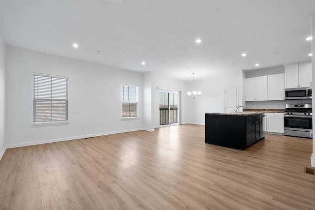 kitchen featuring white cabinets, stainless steel appliances, a center island with sink, and sink