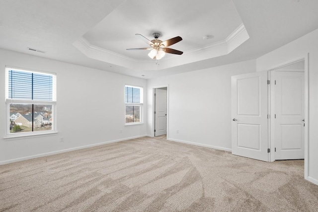 unfurnished room featuring ceiling fan, light colored carpet, ornamental molding, and a tray ceiling