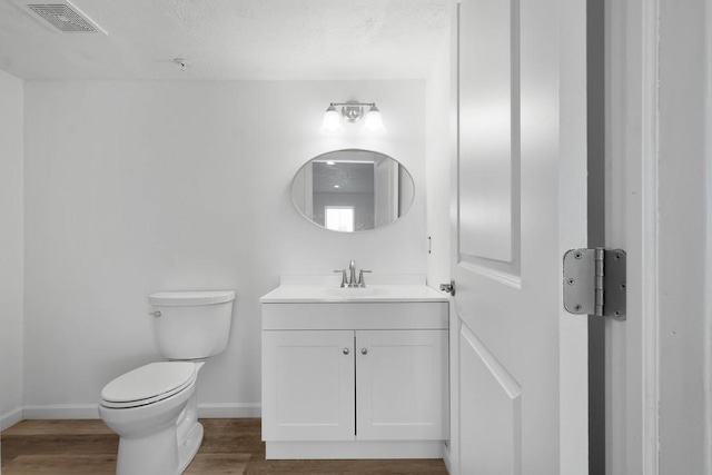 bathroom featuring hardwood / wood-style floors, vanity, toilet, and a textured ceiling