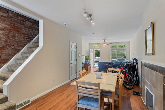 dining space featuring wood-type flooring, ceiling fan, and track lighting