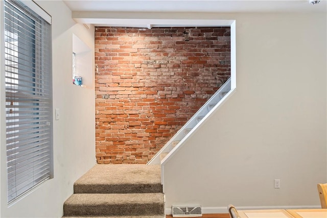 staircase featuring brick wall