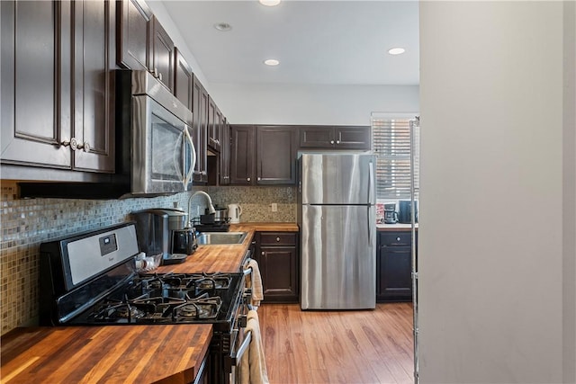 kitchen featuring appliances with stainless steel finishes, sink, wooden counters, decorative backsplash, and light wood-type flooring