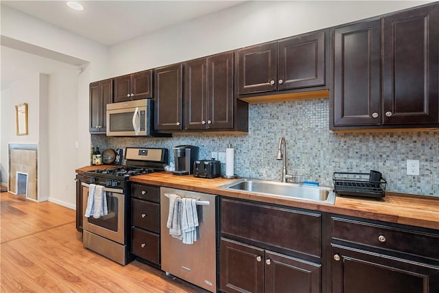 kitchen featuring dark brown cabinetry, stainless steel appliances, sink, and butcher block countertops