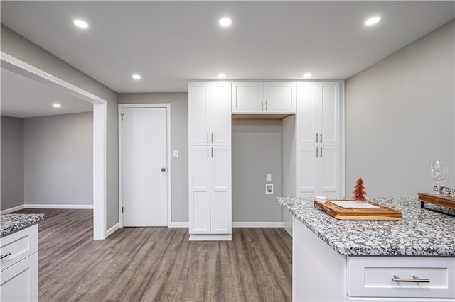 kitchen with wood-type flooring, white cabinetry, and light stone counters