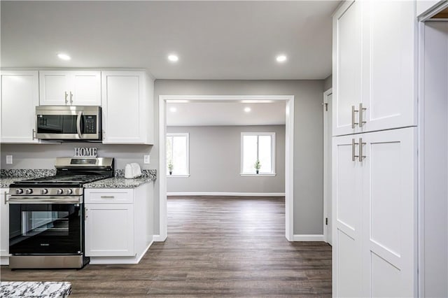 kitchen featuring dark hardwood / wood-style flooring, stainless steel appliances, white cabinetry, and light stone counters