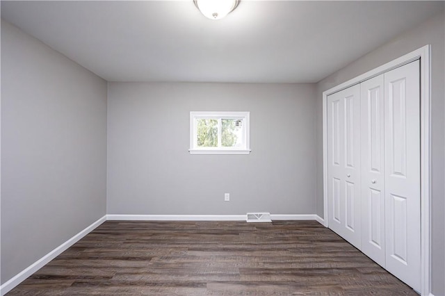 unfurnished bedroom featuring dark hardwood / wood-style flooring and a closet