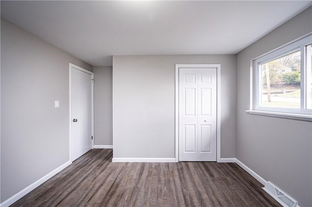 unfurnished bedroom featuring dark hardwood / wood-style floors and a closet