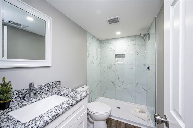 bathroom with vanity, toilet, wood-type flooring, and tiled shower