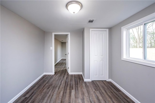 unfurnished bedroom with dark hardwood / wood-style flooring and a closet