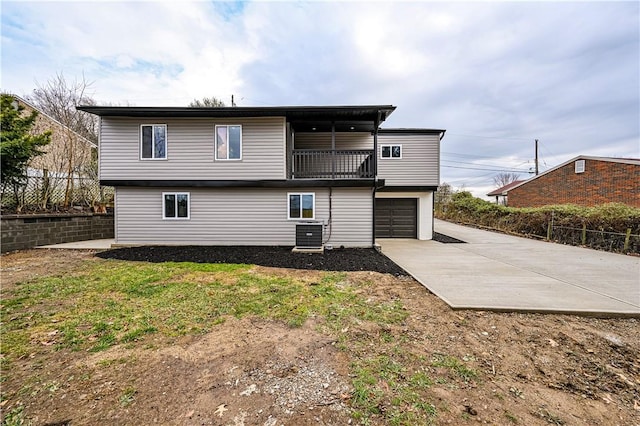 rear view of property with central air condition unit, a balcony, a lawn, and a garage