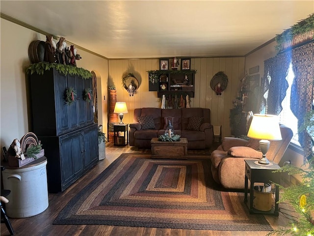 living room with hardwood / wood-style flooring, ornamental molding, and wood walls