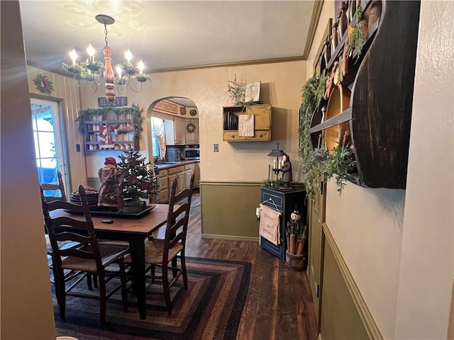 dining space with a chandelier, dark wood-type flooring, and ornamental molding