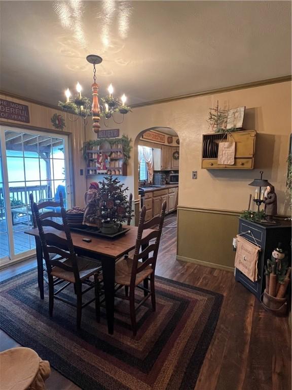 dining area with crown molding, sink, dark hardwood / wood-style floors, and an inviting chandelier