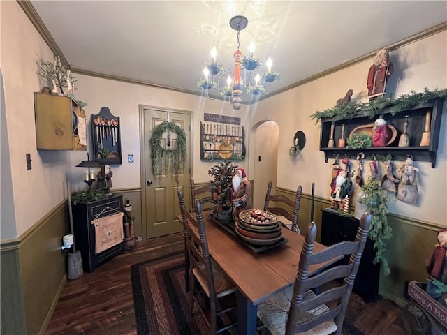 dining space with dark hardwood / wood-style flooring, ornamental molding, and an inviting chandelier