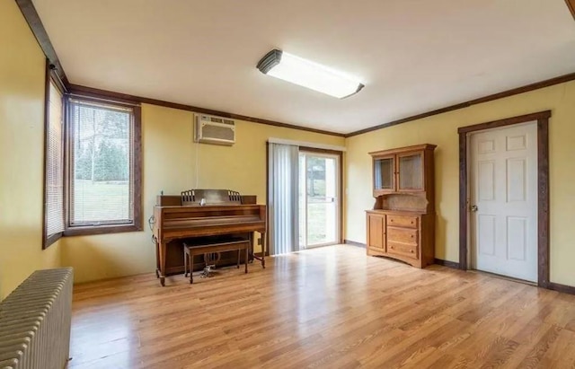 misc room with a wall mounted AC, crown molding, radiator heating unit, and light hardwood / wood-style floors