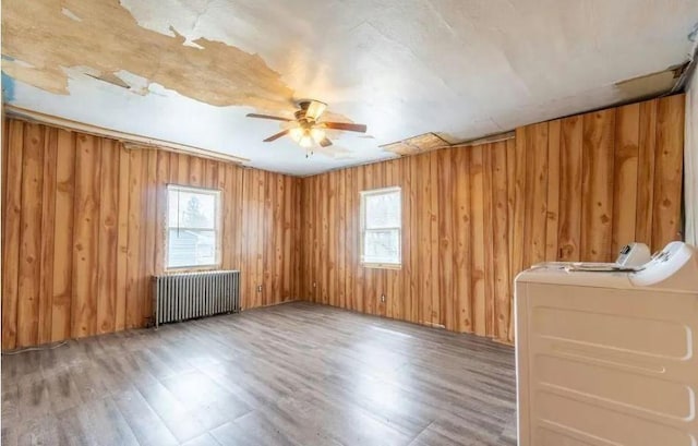 empty room featuring hardwood / wood-style flooring, radiator, and ceiling fan