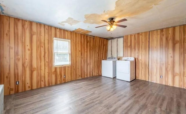 clothes washing area with separate washer and dryer, wooden walls, ceiling fan, and dark wood-type flooring