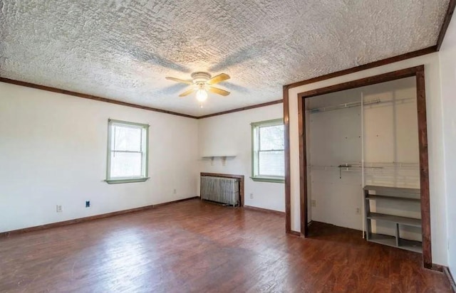 unfurnished bedroom with ceiling fan, dark hardwood / wood-style flooring, radiator heating unit, and multiple windows