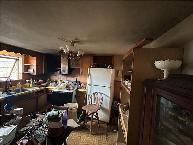 kitchen with backsplash, a notable chandelier, white appliances, and sink