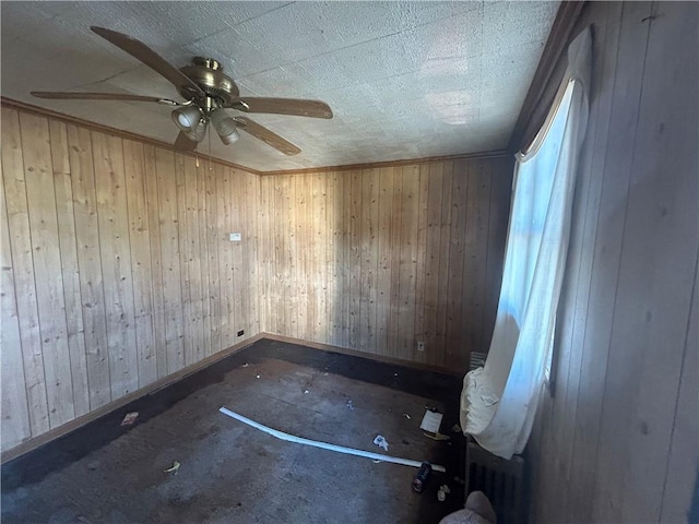 spare room with ceiling fan and wood walls