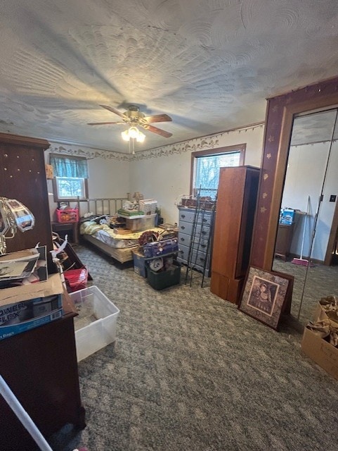 carpeted bedroom with ceiling fan, multiple windows, and a textured ceiling