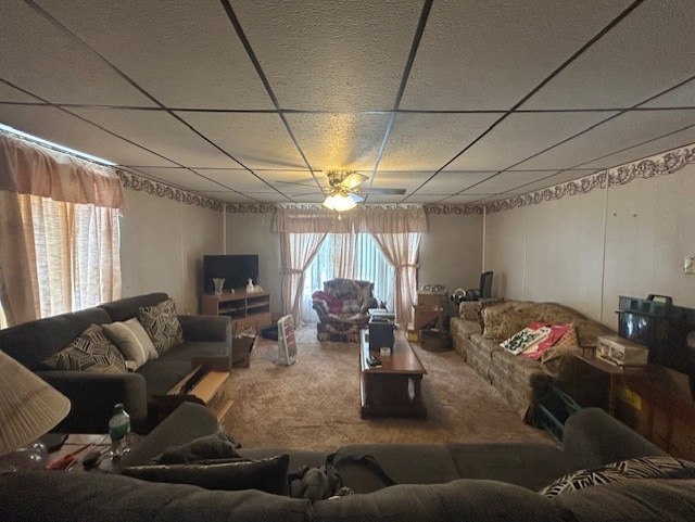 living room featuring ceiling fan, carpet flooring, and a paneled ceiling